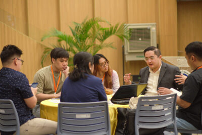 Bradley Cua, resource speaker, engages participants during the gallery walk session, discussing the challenge statement on energy efficiency in industries and offering additional insights.